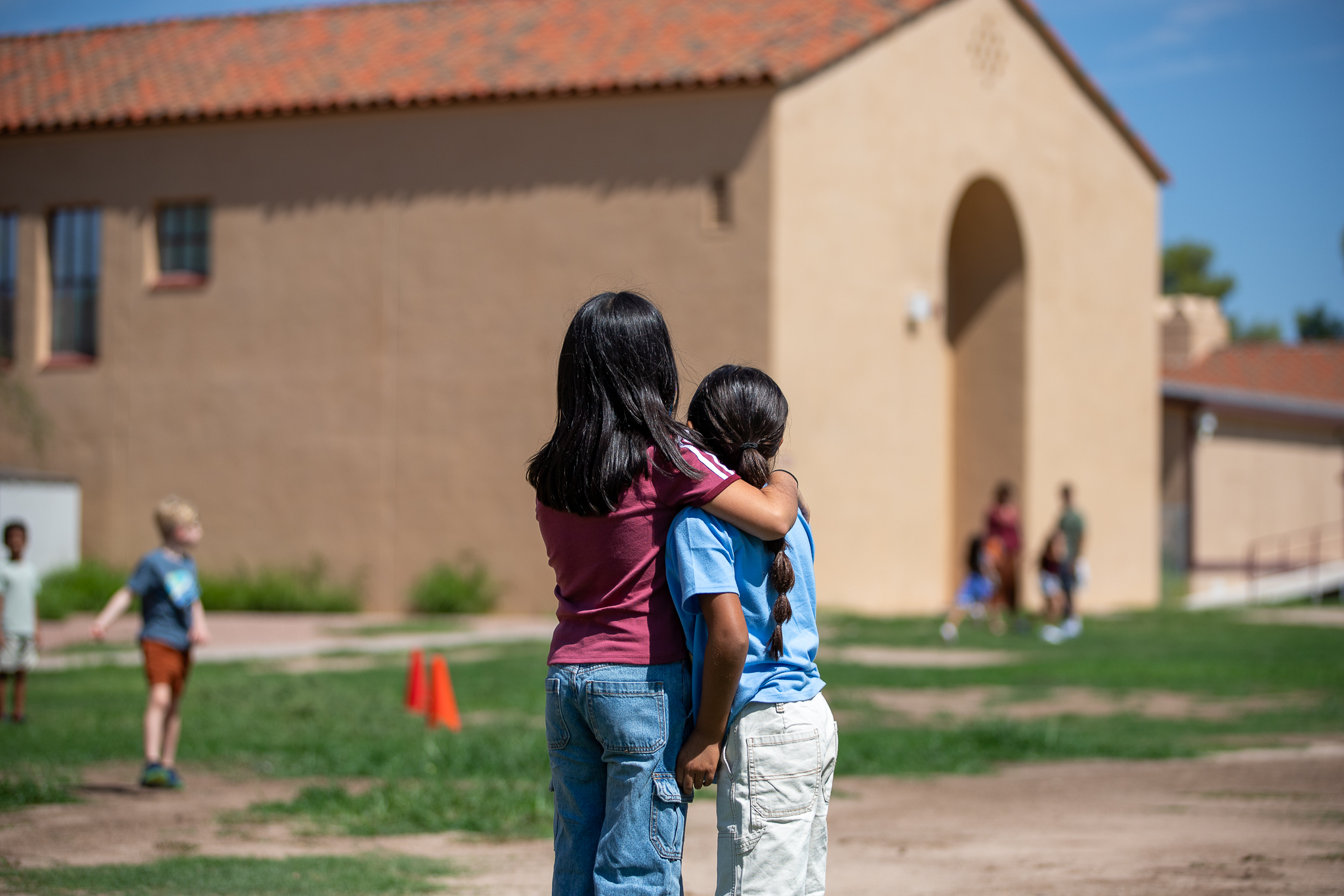 Two girls hug each other outside school on the first day